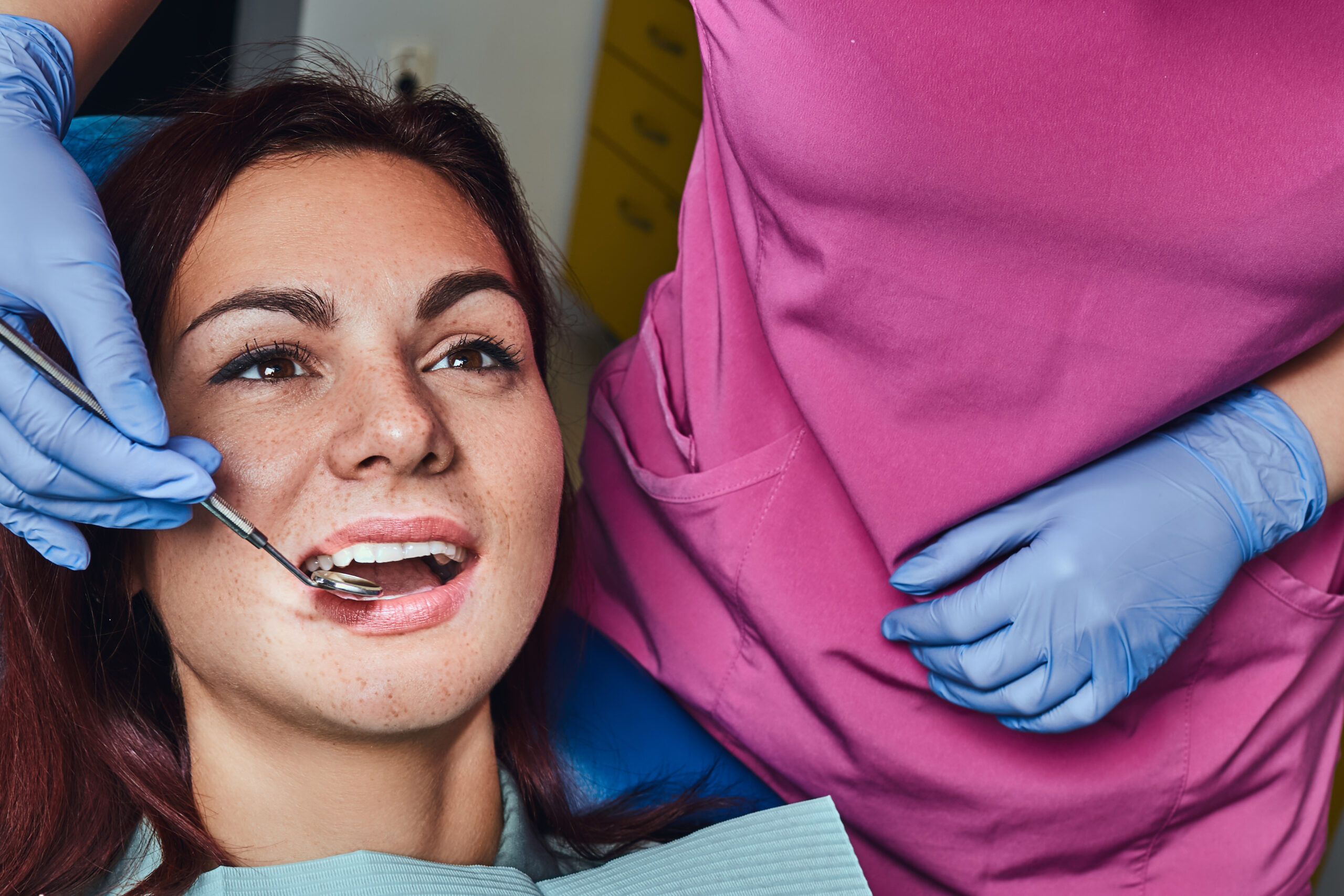 A young woman having examination while sitting in the dentist’s chair with opened mouth.